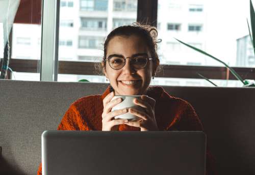 Women Smiles Holding Mug Sitting Behind A Laptop Photo
