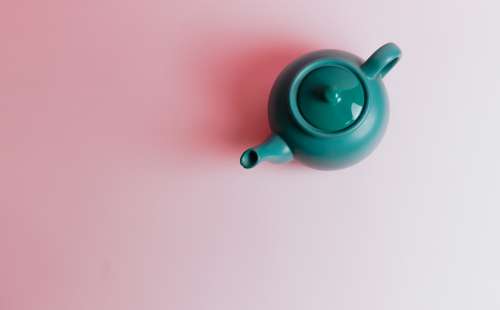 Top View Of A Green Teapot On A Pink Background Photo