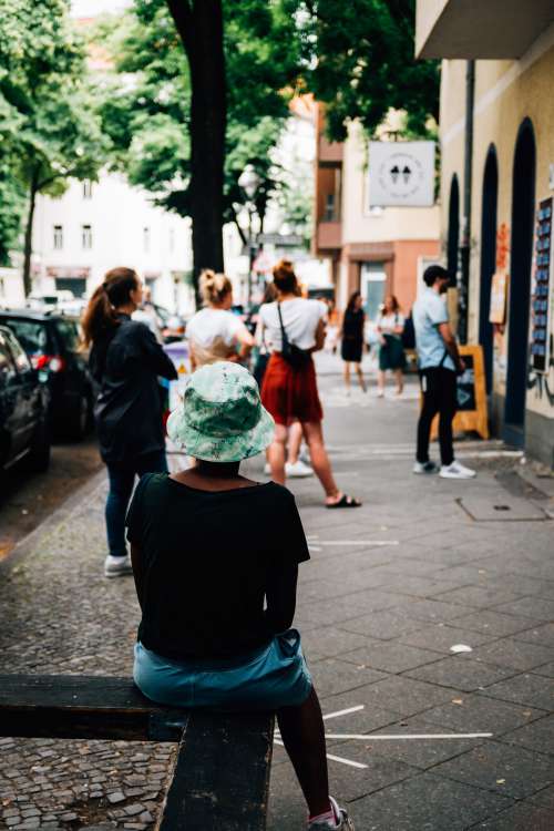 Person Sits Waiting In Line Outside A Shop Photo