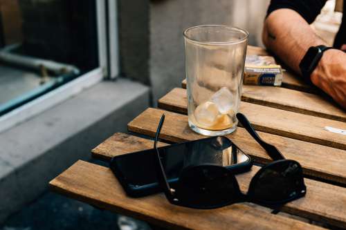 Sunglasses And A Cellphone On A Wooden Picnic Table Photo