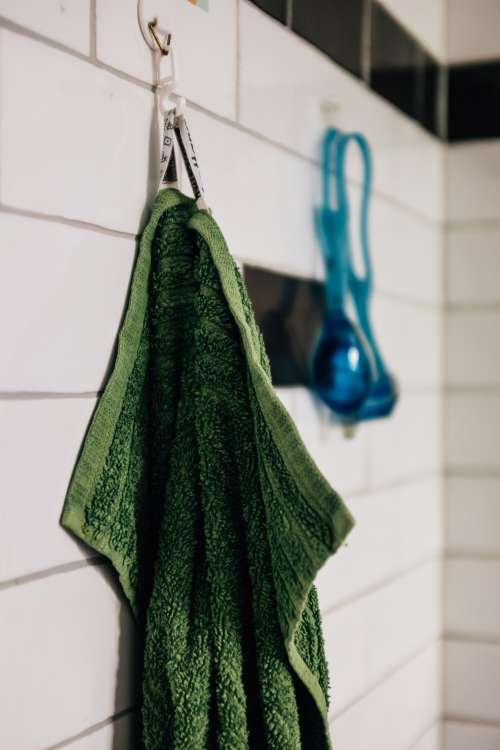 Green Towel Hands On White Tiled Wall Photo