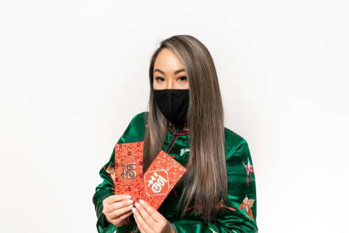 Person In A Facemask Holds Red Metallic Cards Photo