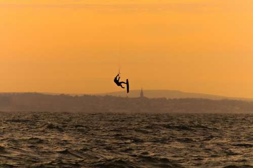 Silhouette Of A Person Kite Surfing In Wavy Water Photo