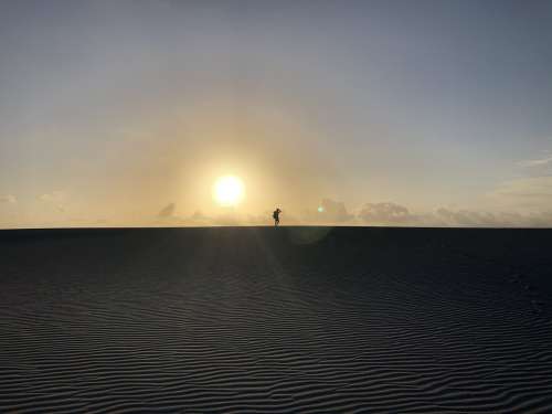 Sunsets In The Desert Silhouetting A Person Photo
