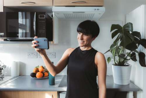 Women Stands In The Kitchen And Takes A Selfie Photo