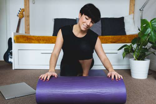 Women Rolls Out A Purple Yoga Mat In Her Living Room Photo