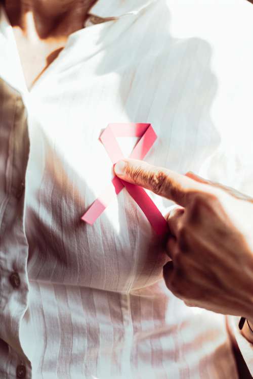 Person In White Holding A Pink Ribbon To Their Chest Photo