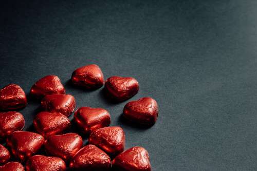 Red Foiled Chocolate Hearts Scattered On Black Photo