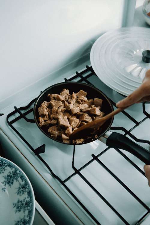 Wooden Spoon Mixes Meat In A Black Frying Pan Photo