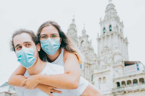 Woman Hugs Man While Wearing Blue Facemask Photo