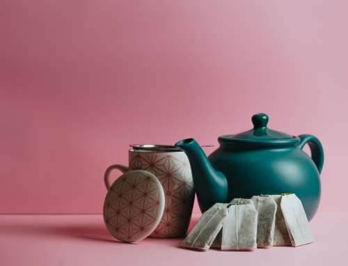A Green Teapot And Teabags Leaning On It Photo