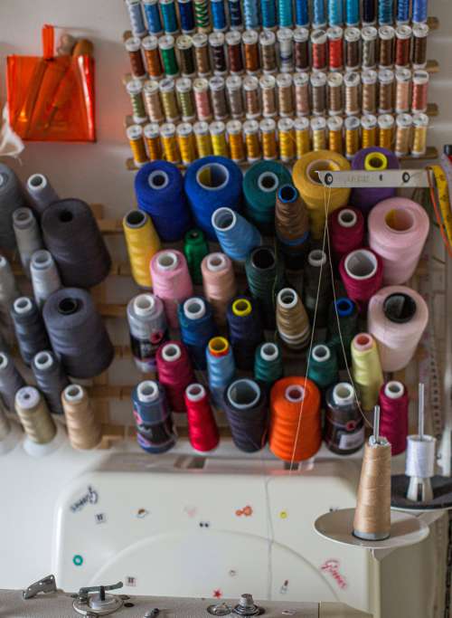 A Wall With Spools Of Thread On A Wooden Rack Photo