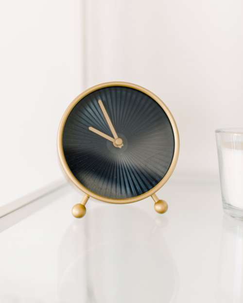 Black And Gold Clock Sits On A White Table Photo