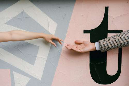 Hands Reach For Each Other Against A Painted Wall Photo