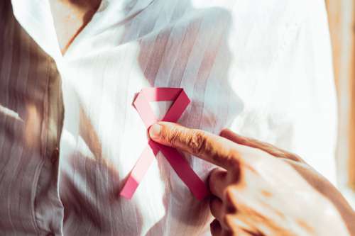 Close Up Of A Person Holding A Pink Ribbon On Their Chest Photo