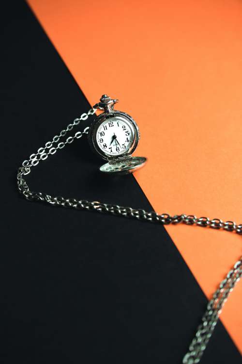 A Pocket Watch Laying On A Black And Orange Background Photo