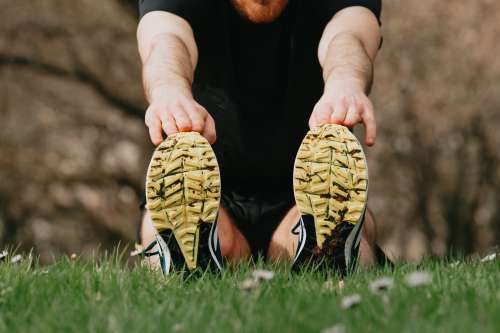 Running Shoes On Green Grass of A Person Stretching Photo