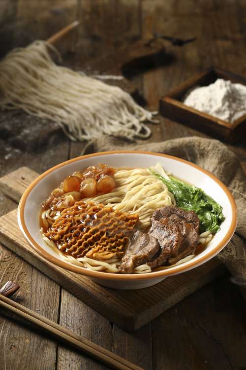 Steaming Bowl Of Noodle Soup On A Wooden Surface Photo