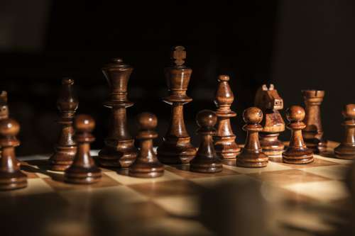 Dark Wooden Chess Pieces Against A Black Background Photo
