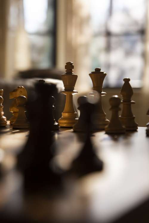 Chess Pieces In Focus On A Wooden Chess Board Photo