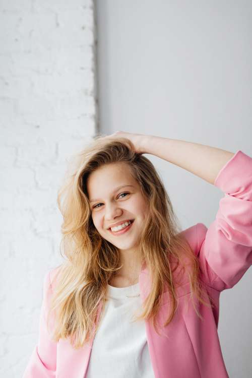 Beautiful teenage girl with long blonde hair wearing a pink jacket