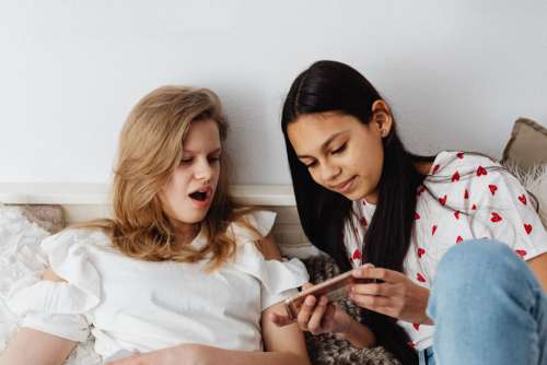 Teens sit together on the couch and use phones