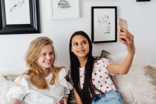 Teens sit together on the couch and use phones