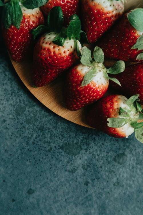 Strawberries On A Wooden Plate Over Black Surface Photo