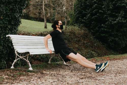 Person Holds The Edge Of A Bench While Stretching Photo