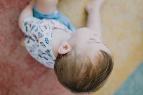 Camera Looks Down At A Small Child On Colorful Rug Photo