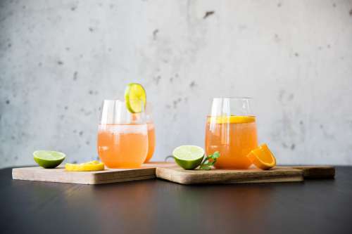 Two Cocktails Sit On Wooden Boards Surrounded By Citrus Photo