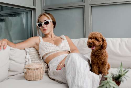 Woman Leans Back On A White Couch With A Small Puppy Photo