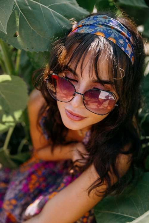 Woman In Bold Sunglasses Surrounded By Green Leaves Photo