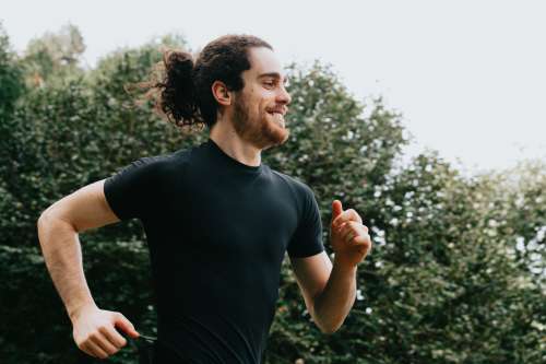 A Person In Black Smiling As They Run Outdoors Photo