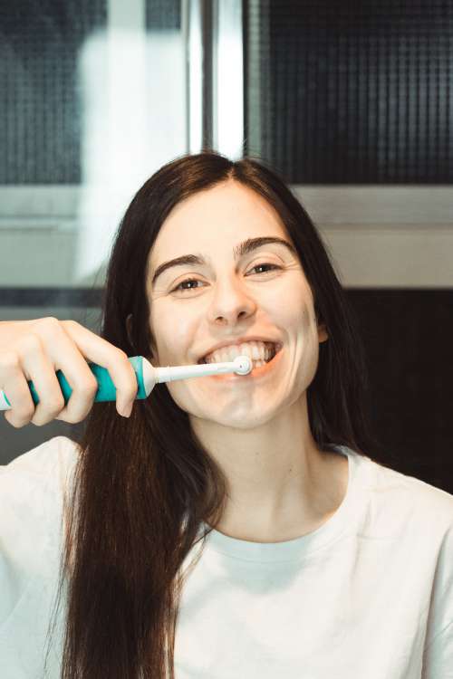 Woman Brushes Her Teeth With An Electric Toothbrush Photo