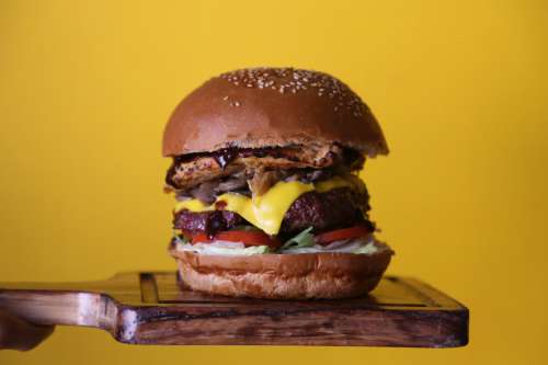 Stacked Cheeseburger On Yellow Background Photo