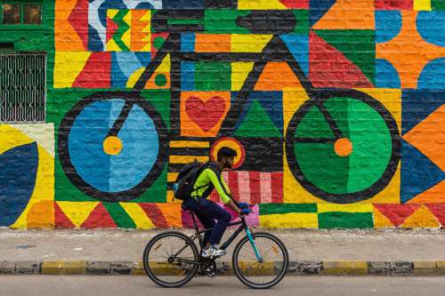 Person Rides A Bike With A Mural Of A Bike Behind Them Photo
