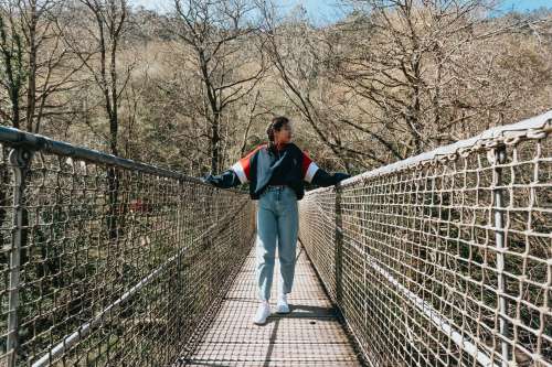 Person Stands On A Bridge With One Hand On Each Railing Photo