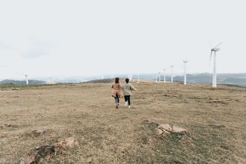 Two People Walk Among Tall White Windmills Photo