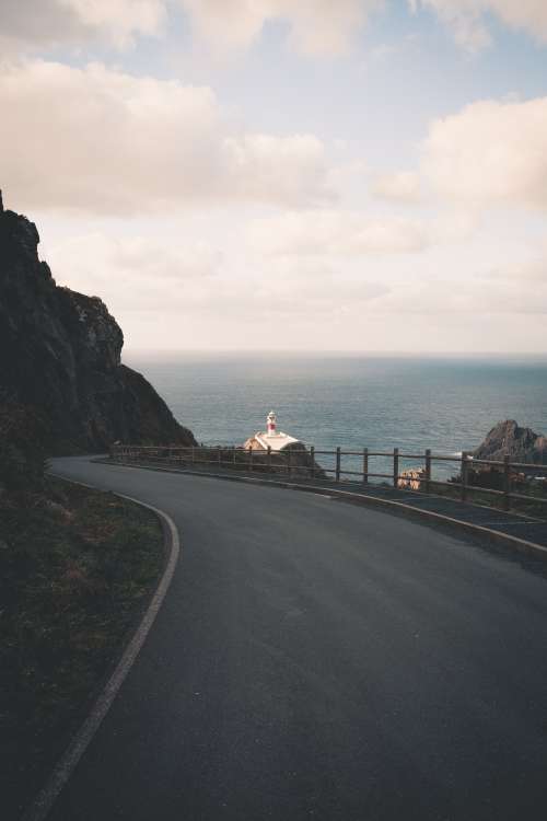 Winding Paved Road With A Lighthouse In The Distance Photo