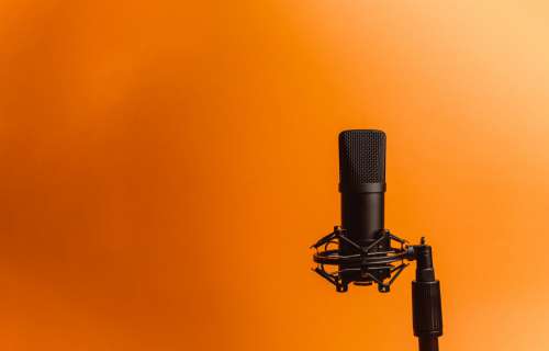 Black Microphone Against A Vibrant Orange Background Photo