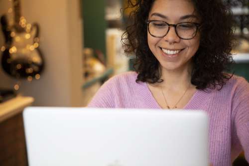 Person Wears Glasses And Smiles At Their Laptop Photo