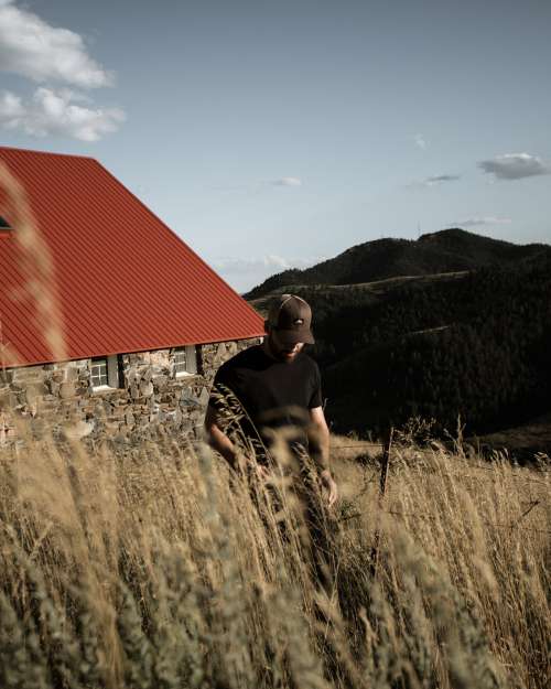 Person Stands In Golden Wheat With A Building Behind Photo