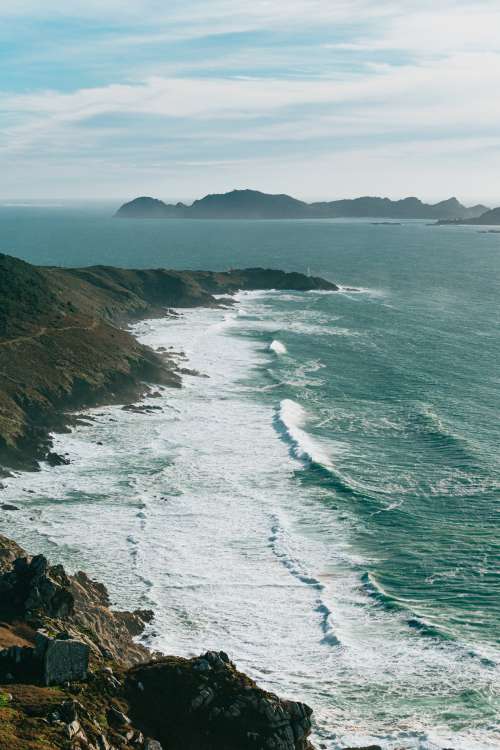 Cliff Side View Of Wavy Ocean And Large Hills Photo