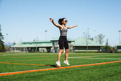 Woman Mid Jumping Jack Floats Above Green Grass Photo