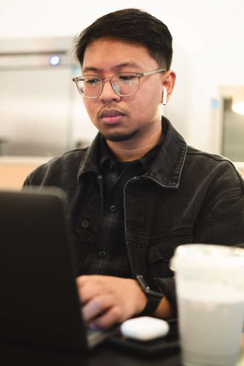 Man Looks At His Laptop And Types Photo