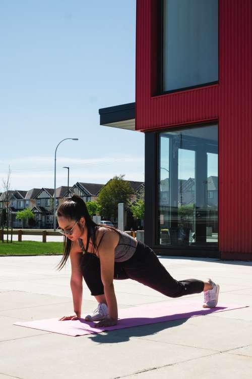 Woman Lunges Forwards On A Pink Yoga Mat Outdoors Photo