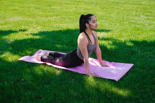Woman Practices Yoga In Green Grass Photo