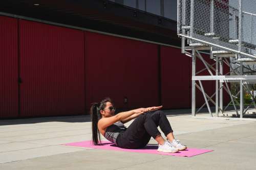 Woman On A Pink Yoga Mat Crunches Forward Photo