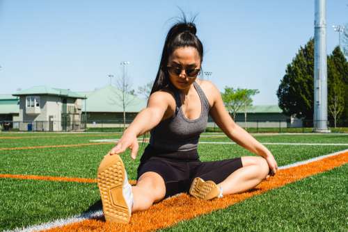 Woman Stretches On A Sports Fields Grass Photo
